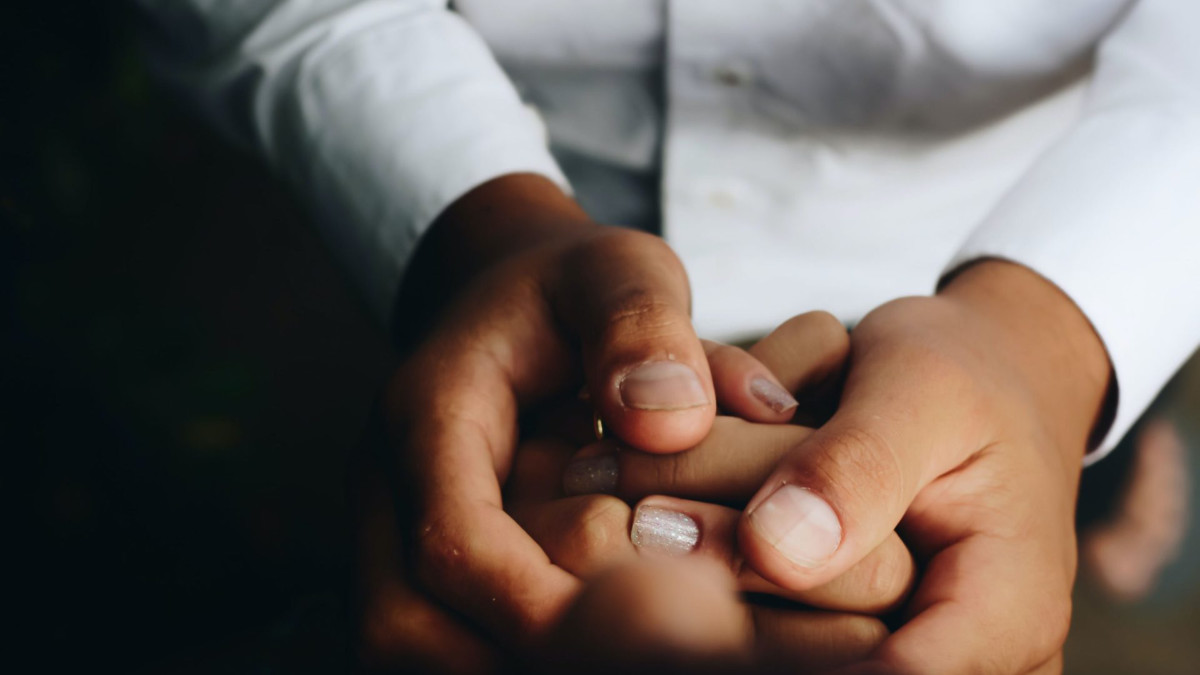 Close-up of an adult's hands gently holding a child's hand