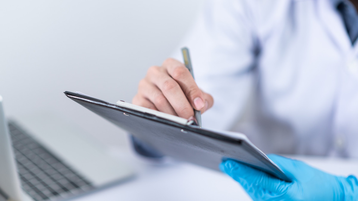 Clinician wearing gloves writing notes on a tablet